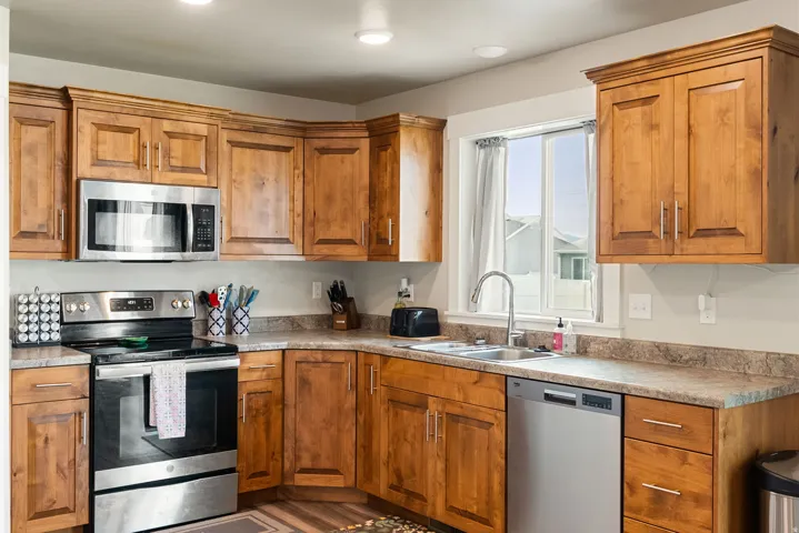 Kitchen featuring wood cabinetry, stainless steel appliances, a double basin sink, and ample countertop space
