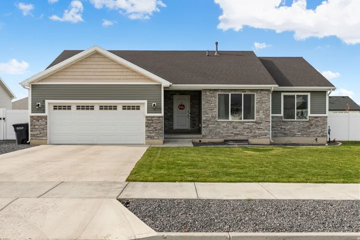 Exterior featuring a stone and siding facade, an attached two-car garage, a concrete driveway, a front lawn, and a dark asphalt shingle roof