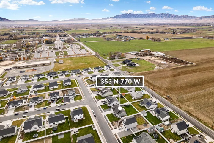 Aerial perspective of a developed residential area with a prominent church structure and surrounding agricultural fields