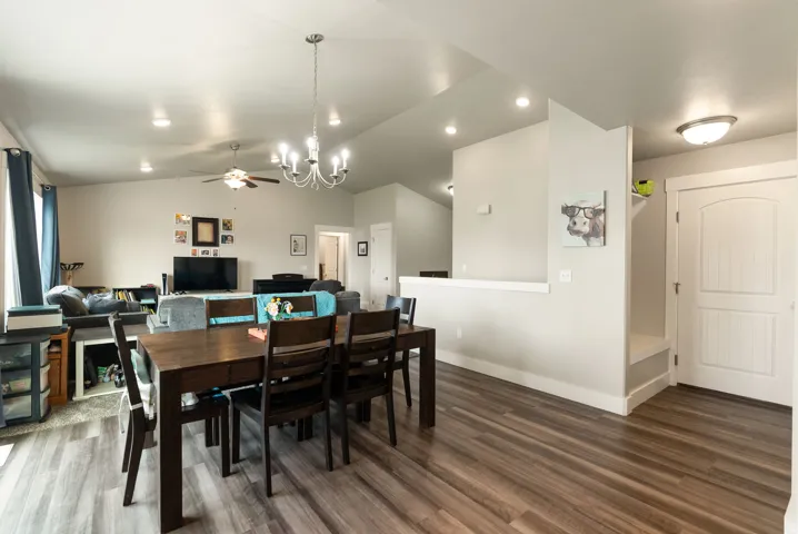 Open-concept living space with wood-finish flooring, recessed lighting, and a decorative chandelier