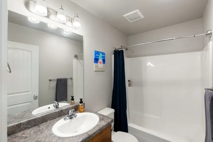 Bathroom with wood-finish vanity, integrated sink, and laminate countertop