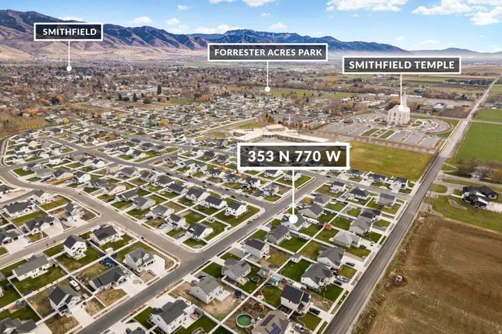 Aerial perspective showcasing an established residential neighborhood, featuring uniform single-family homes with dark roofs and light-colored exteriors, organized along paved streets