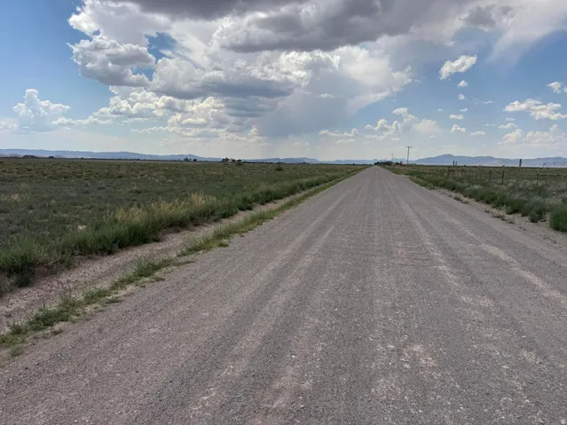 Gravel road extending through open terrain with distant mountains