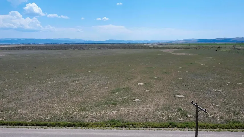 Expansive land parcel featuring natural ground cover and distant mountainous terrain