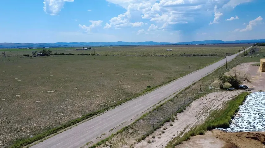 Expansive open land with a gravel road, distant mountain range, and scattered structures
