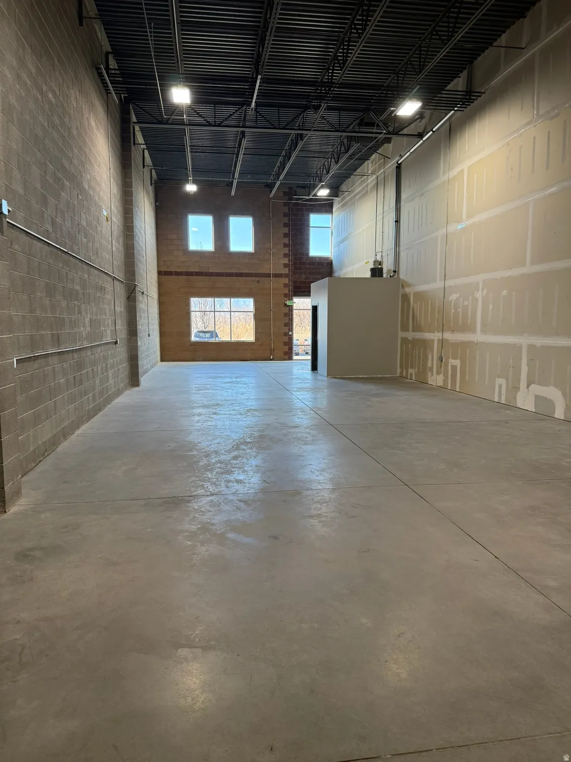 Spacious interior with exposed steel beam ceiling, concrete flooring, and ample natural light from multiple windows