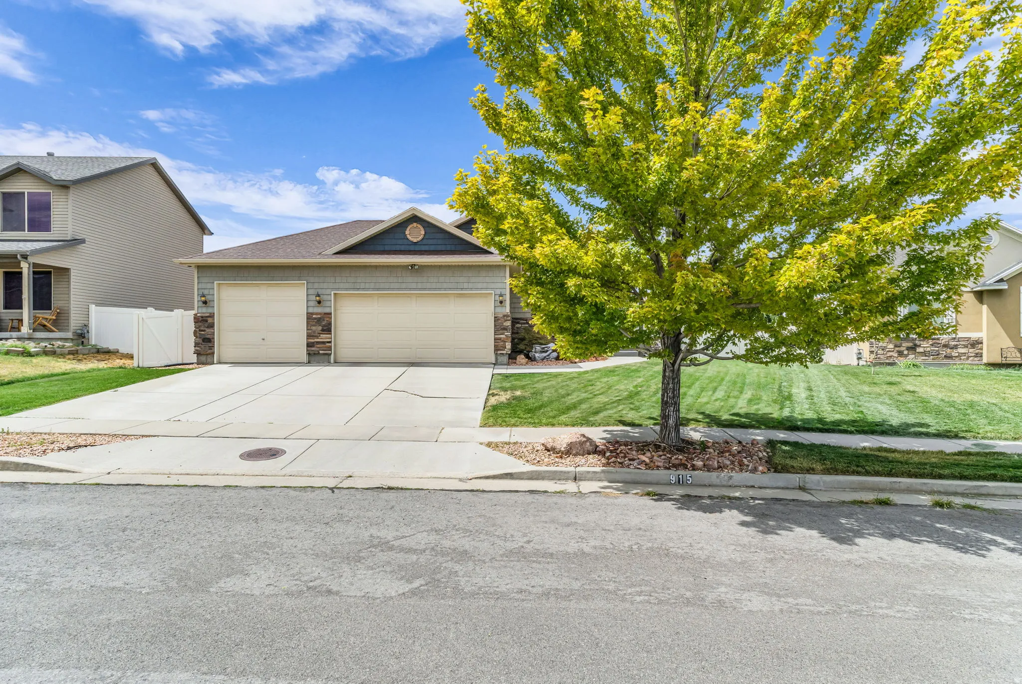 Two-car garage with overhead doors, stone veneer accents, and a gabled roofline