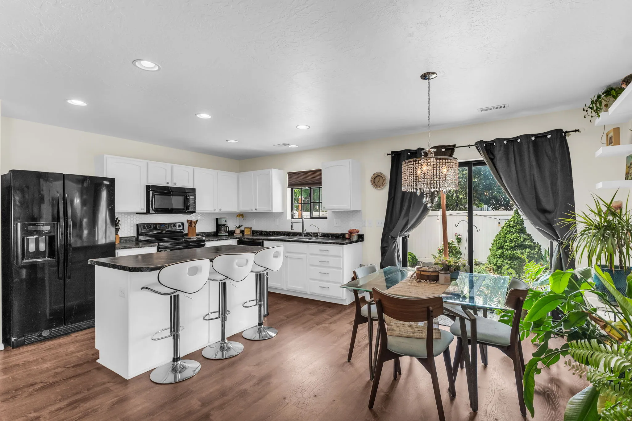 White kitchen cupboards and black appliances.