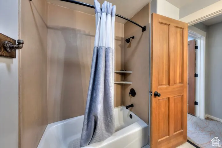 Tub and shower combination with dark bronze fixtures and integrated shelving