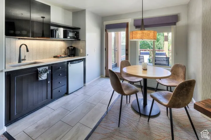Kitchenette featuring dark-stained cabinetry, a light-toned countertop, and a chevron-patterned tile backsplash