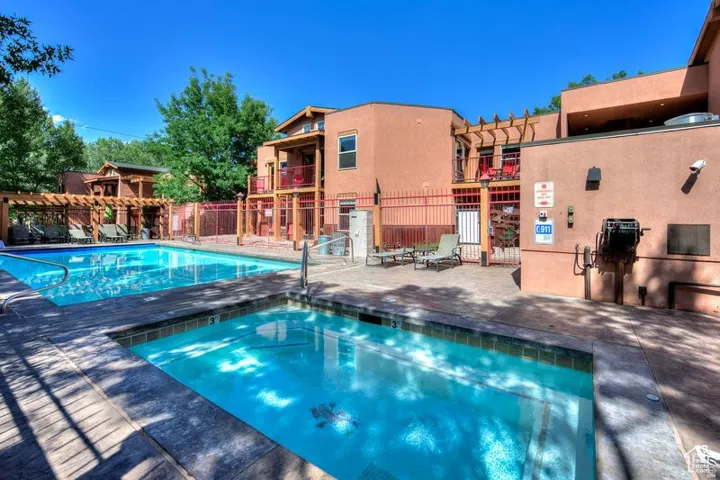 Outdoor swimming pool with integrated spa and surrounding concrete decking