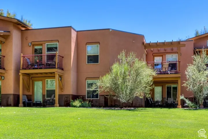 Stucco exterior with private balconies featuring metal railings and wood support beams