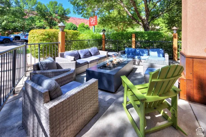 Outdoor patio featuring a built-in fire pit, privacy hedging, and railing