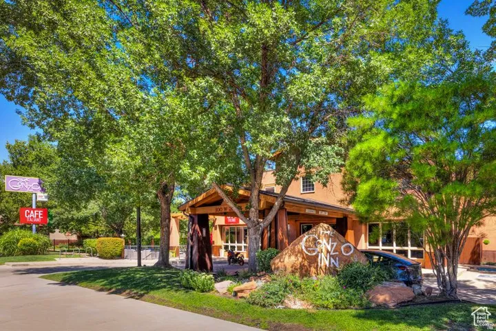 Property entrance featuring mature trees, landscaped rock features, and a covered entry