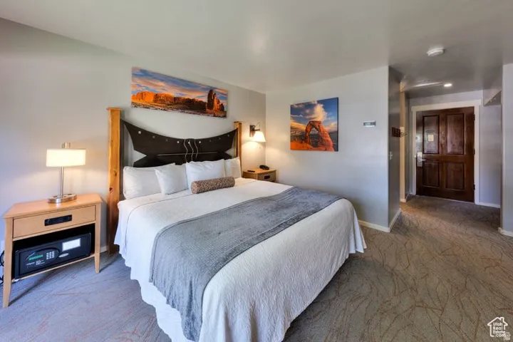 Neutral wall color, patterned carpeting, and a dark wood paneled door