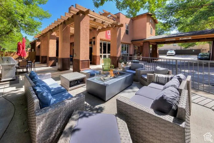 Outdoor lounge area featuring a fire pit, concrete patio, and a pergola structure