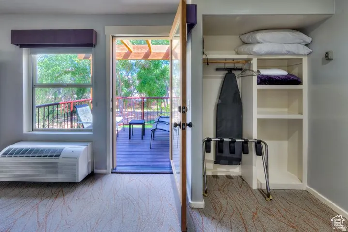 Built-in closet with shelving, outdoor balcony access, integrated air conditioning unit, and wood-finish door frame