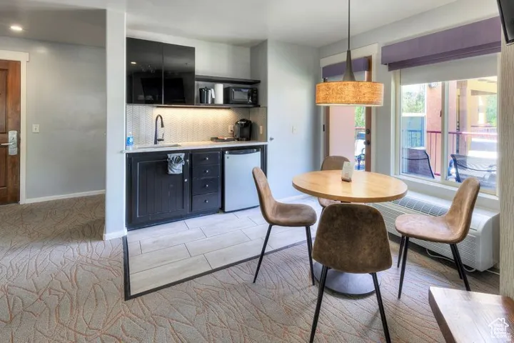 Compact kitchen area with black cabinetry, a white herringbone tile backsplash, and a built-in microwave