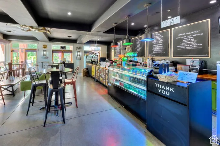 Modern commercial interior featuring a polished concrete floor, recessed and pendant lighting throughout, and a service counter with blue cabinetry and integrated display cases