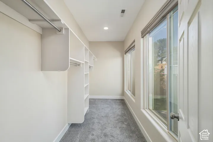 Integrated custom closet shelving, hanging rods, recessed ceiling lighting, and carpet flooring