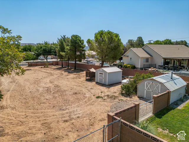 Expansive open lot with two storage sheds, a block wall perimeter, and mature trees