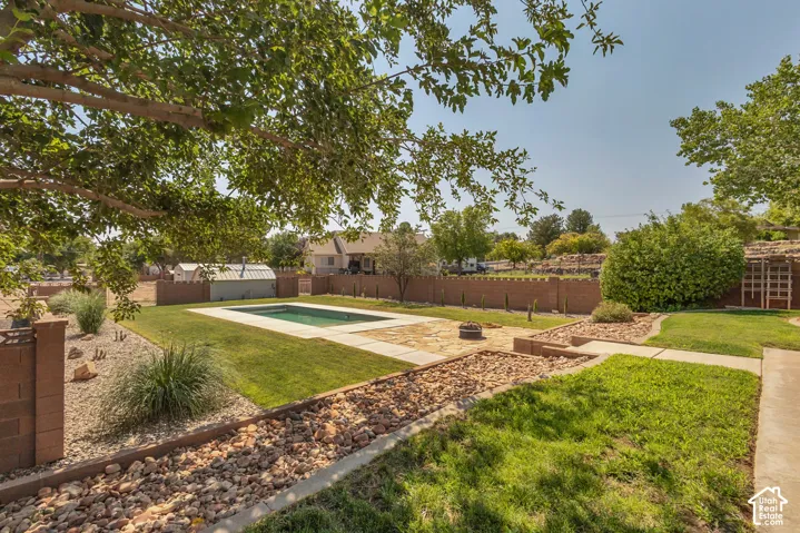 Expansive backyard featuring a manicured lawn, a swimming pool with concrete surround, and a brick privacy fence