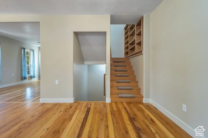 Hardwood flooring throughout, built-in shelving, staircase with carpet treads, and neutral wall paint