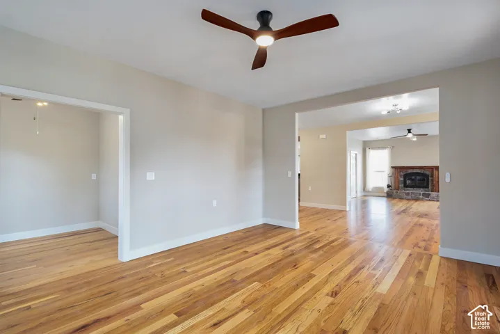 Wood-finish flooring throughout, ceiling fan with integrated lighting, recessed lighting, and a stone-clad fireplace with wood mantle