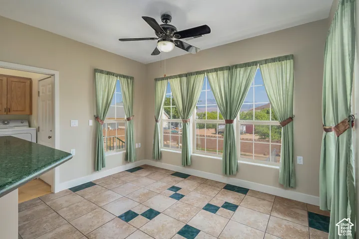 Room featuring a ceiling fan with integrated lighting, multiple windows with grid patterns, and two-tone floor tiling