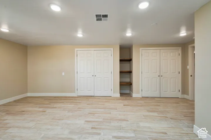 Recessed ceiling lighting illuminates a spacious room featuring wood-look tile flooring