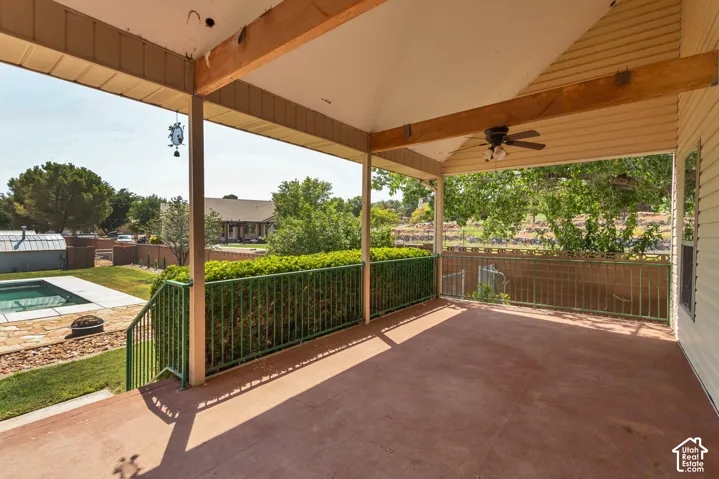 Covered patio featuring a ceiling fan, wood support beams, and metal railings