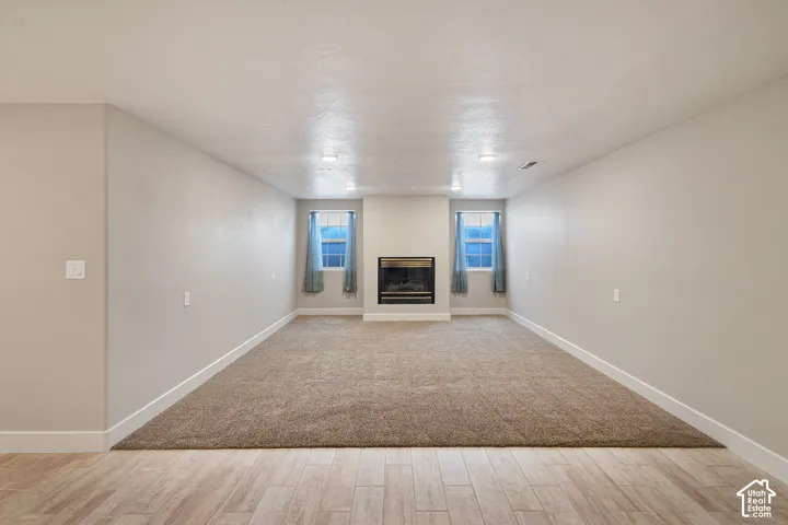 Recessed lighting illuminates the carpeted living area with a built-in fireplace and two windows