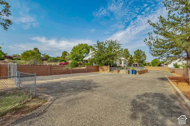 Expansive gravel parking area with chain-link fencing and a block wall perimeter