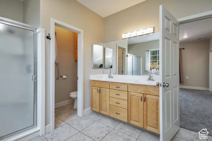 Primary suite with Light wood-finish double vanity with dual sinks, a large mirror, and overhead vanity lighting