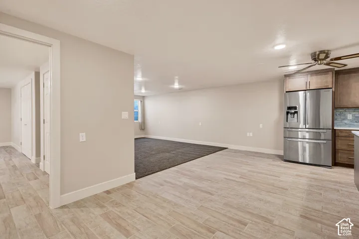 Wood-finish tile flooring, recessed lighting, and a stainless steel refrigerator
