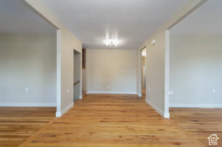 Expansive wood-finish flooring throughout, neutral wall tones, recessed lighting, and a built-in shelving unit