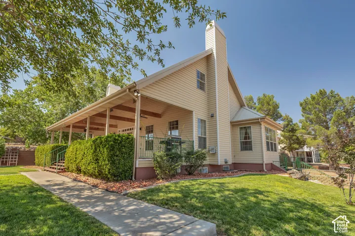 Siding exterior with a covered porch, established landscaping, and a chimney feature
