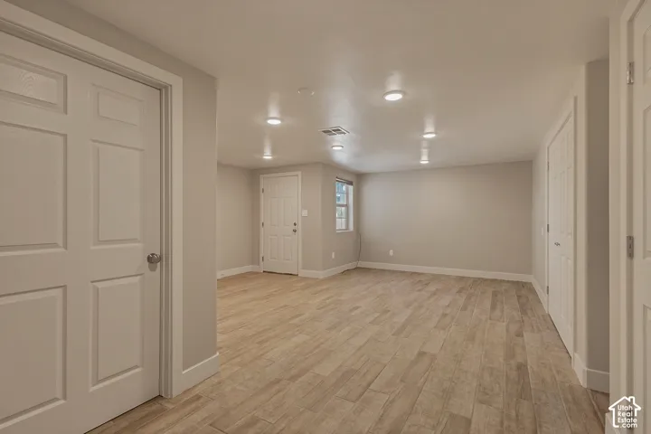 Recessed lighting, wood-finish flooring, white trim, and neutral wall tones