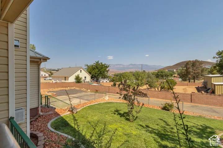 Manicured lawn with a curved landscape border, surrounded by a low brick wall and distant mountains