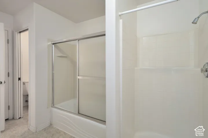 Bathtub with sliding glass enclosure, shower with tile surround, and chrome fixtures