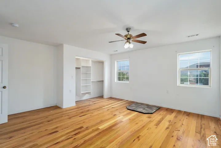 Wood-finish flooring, built-in open shelving, two windows, and a ceiling fan with light fixture