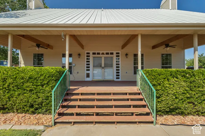 Covered front porch with wood flooring, metal roof, and exposed wood beams