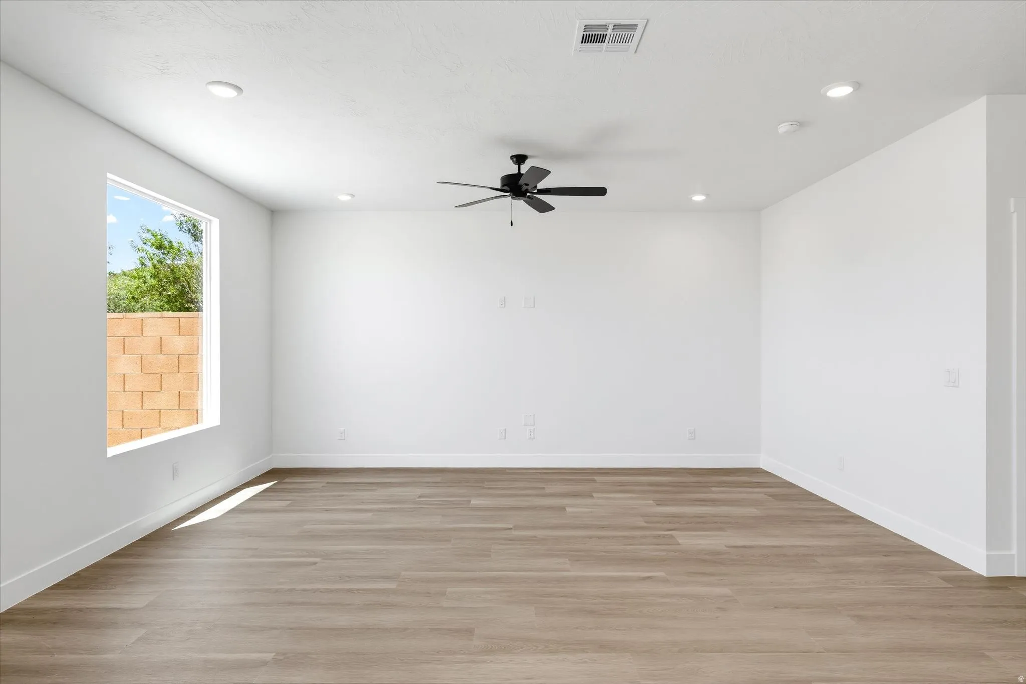 Light-toned wood-finish flooring, recessed lighting, and a modern ceiling fan