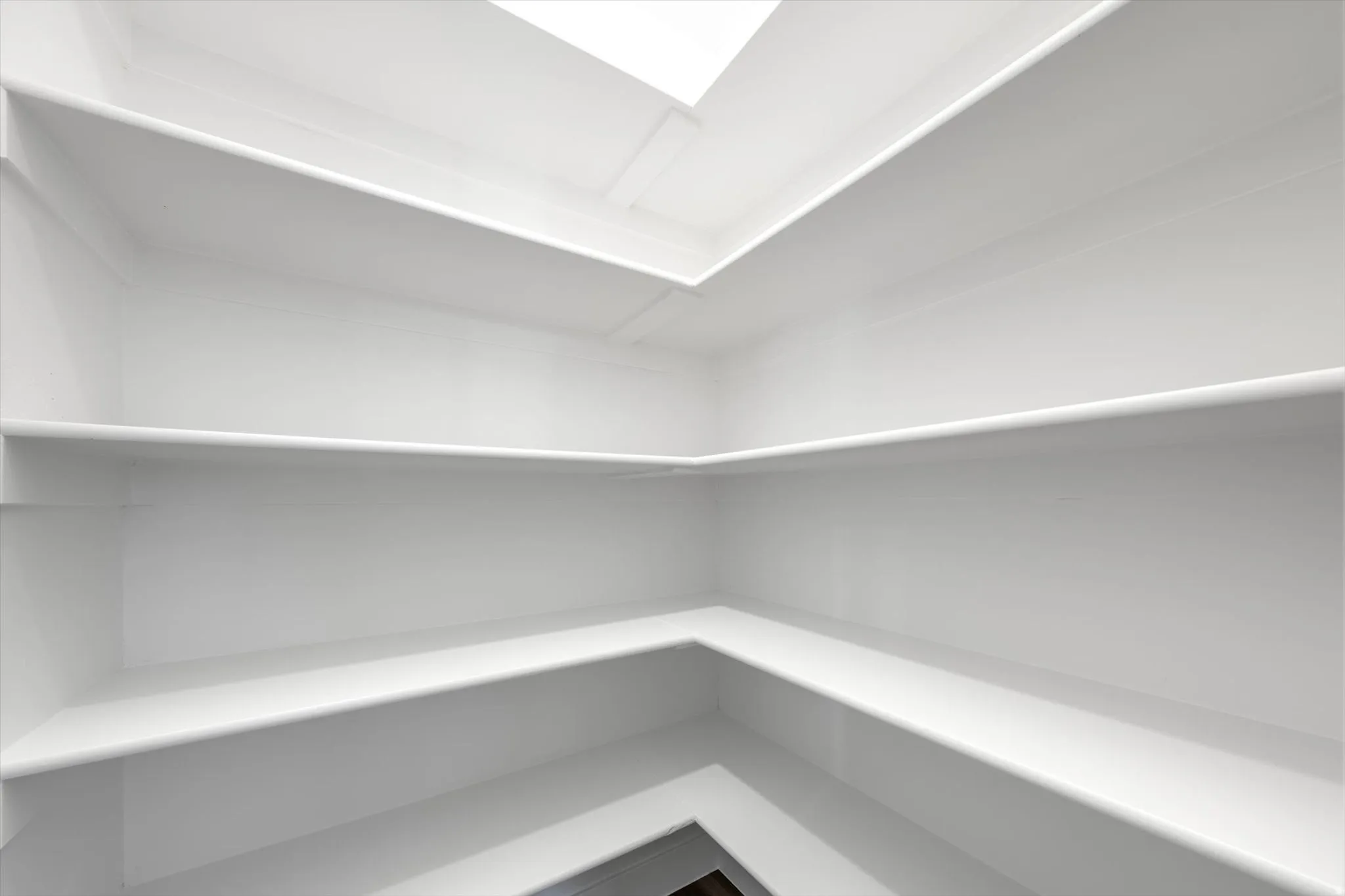 Built-in shelving with multiple levels, white finish, and natural light from above