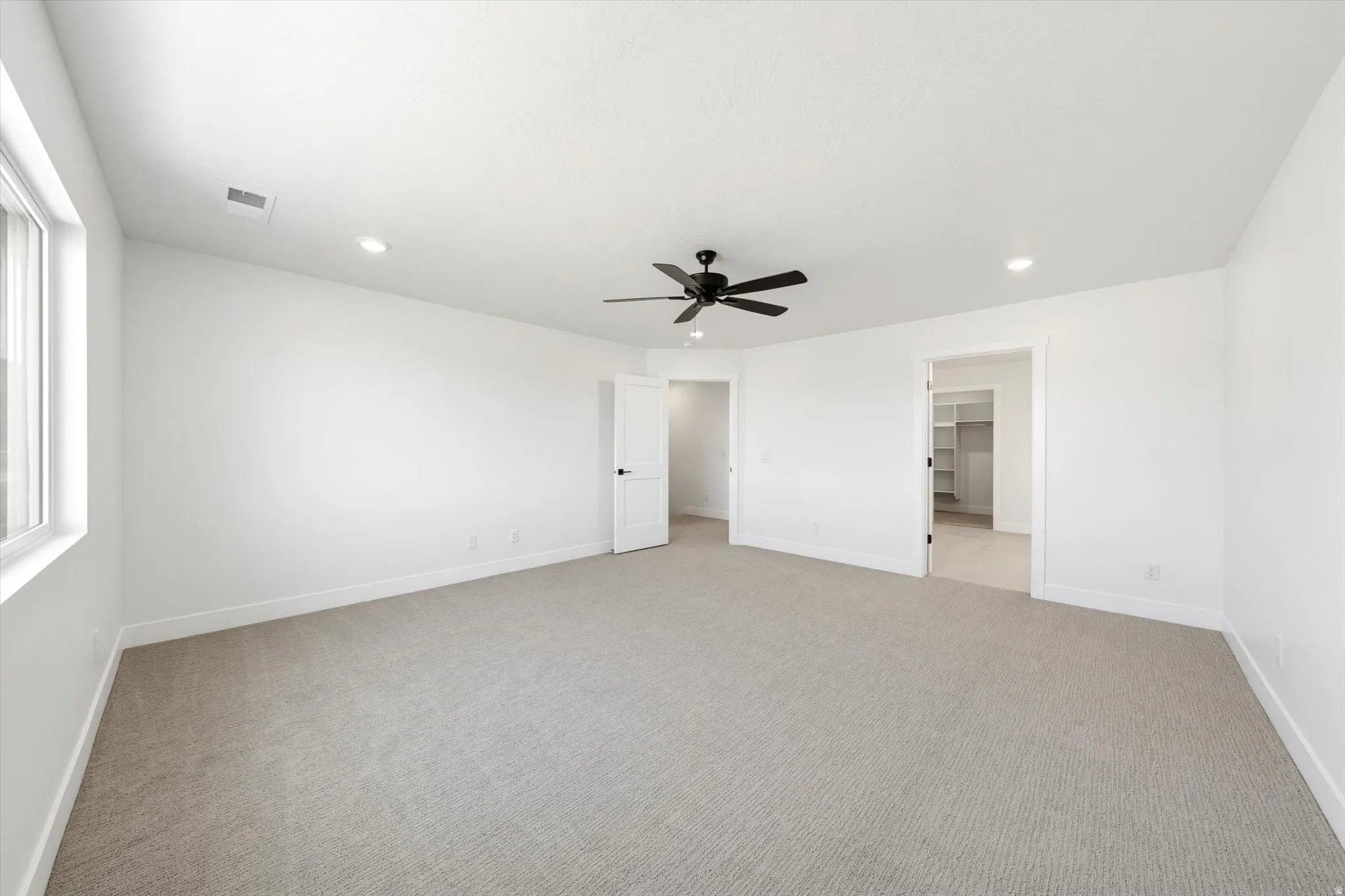 Spacious room featuring neutral carpet, white walls, recessed lighting, and a modern ceiling fan