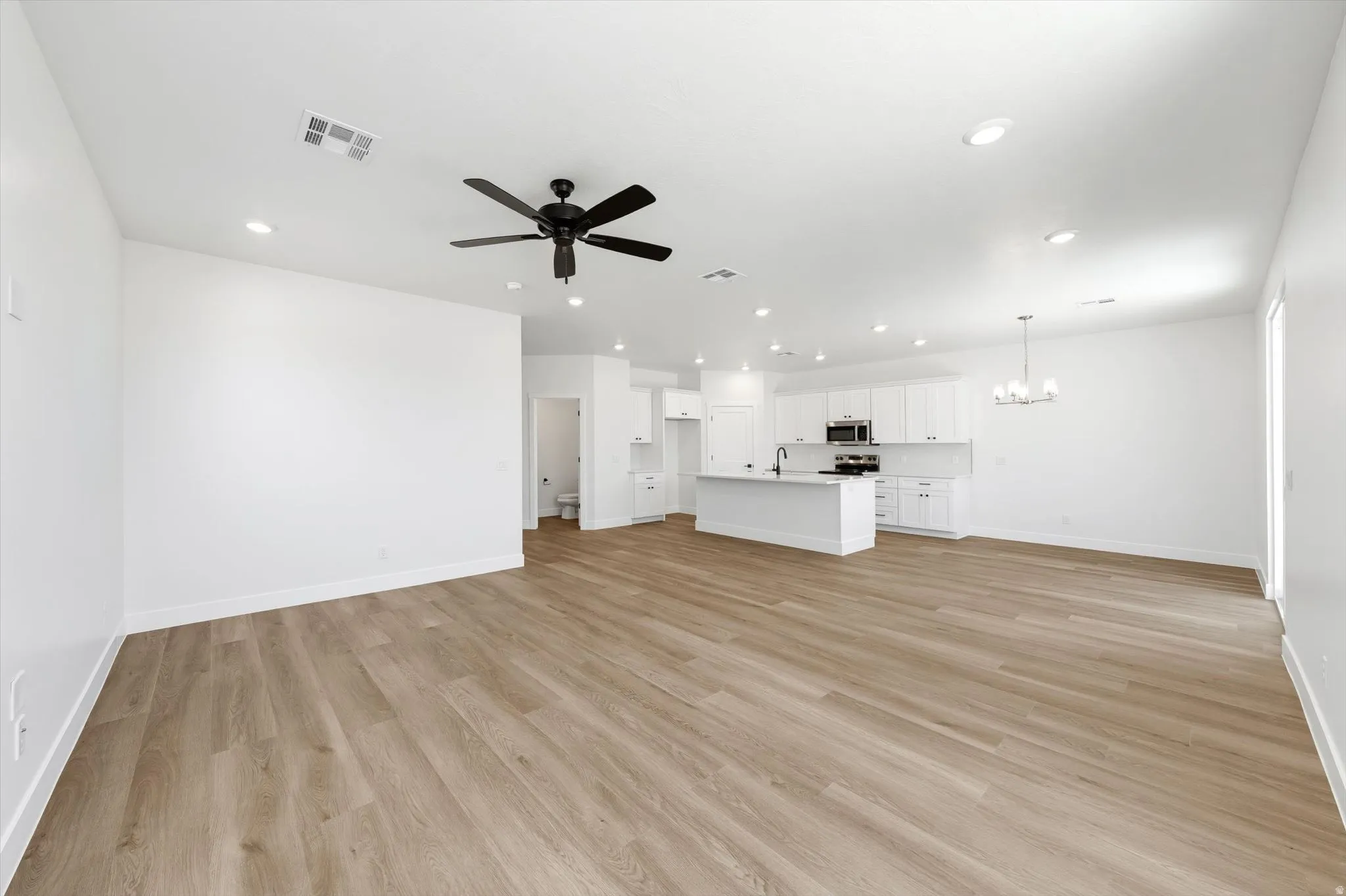 Open-concept living area featuring wood-finish flooring, recessed lighting, and a contemporary ceiling fan