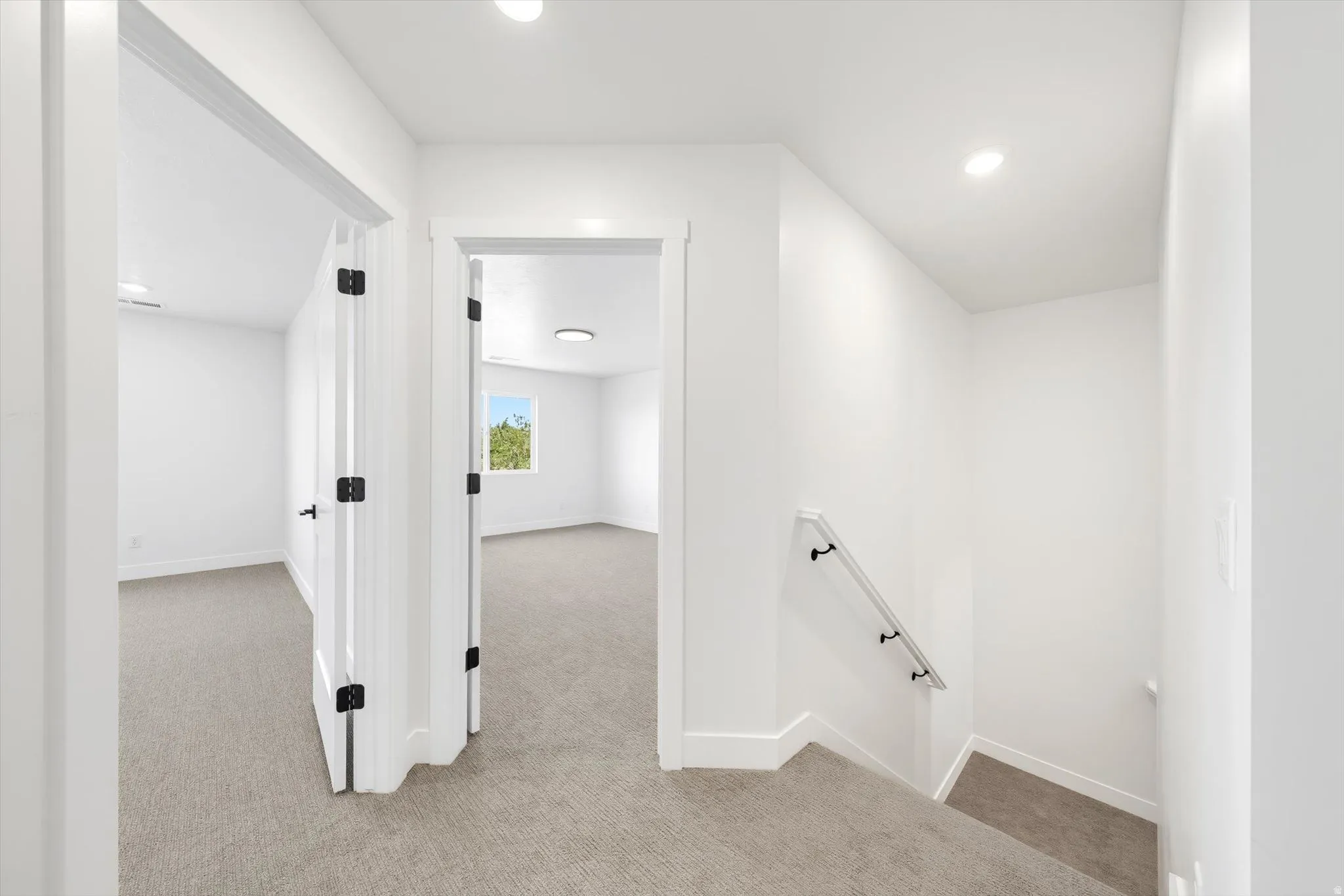 Clean white walls, recessed lighting, and light-toned carpeted flooring define this interior space