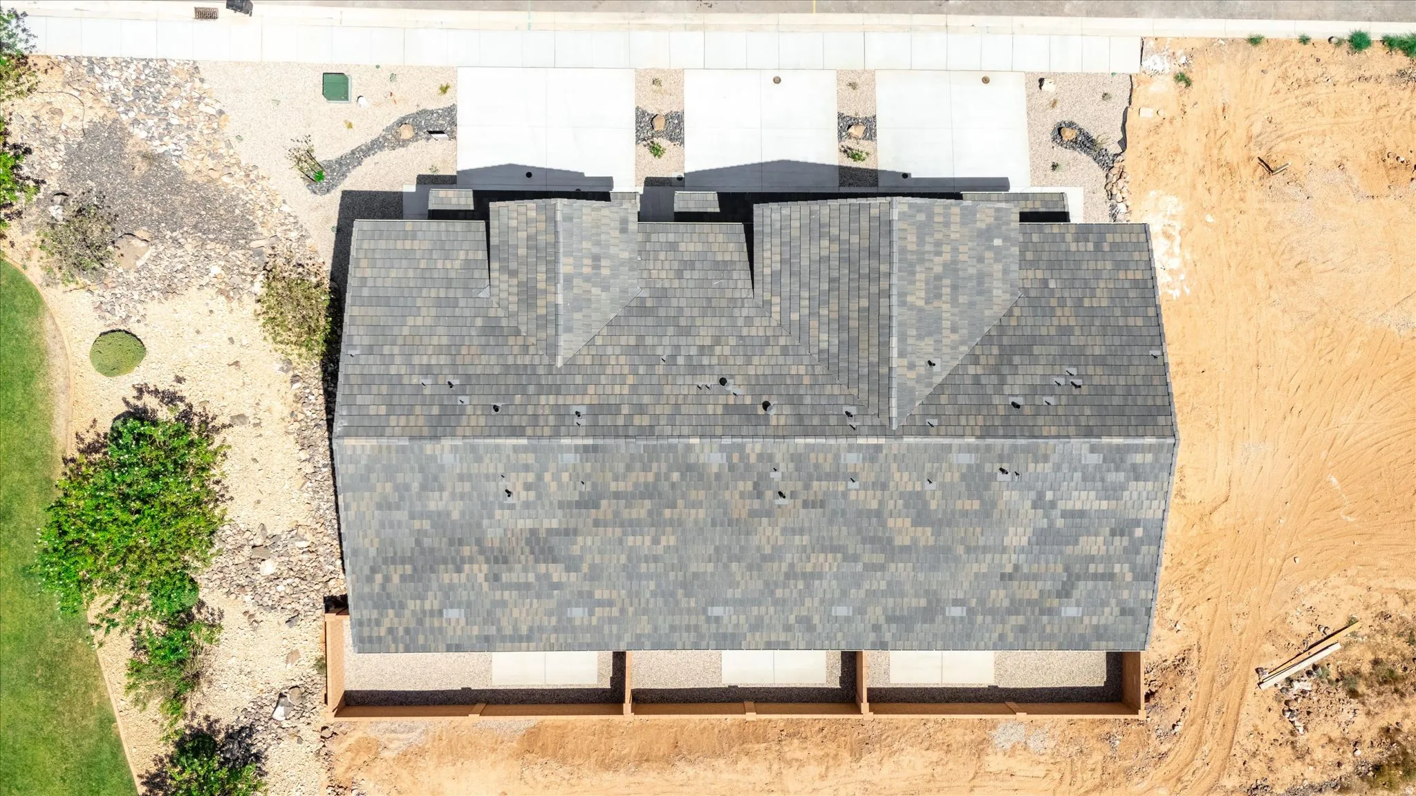 Pitched roof with asphalt shingles, concrete driveway, and partial fencing