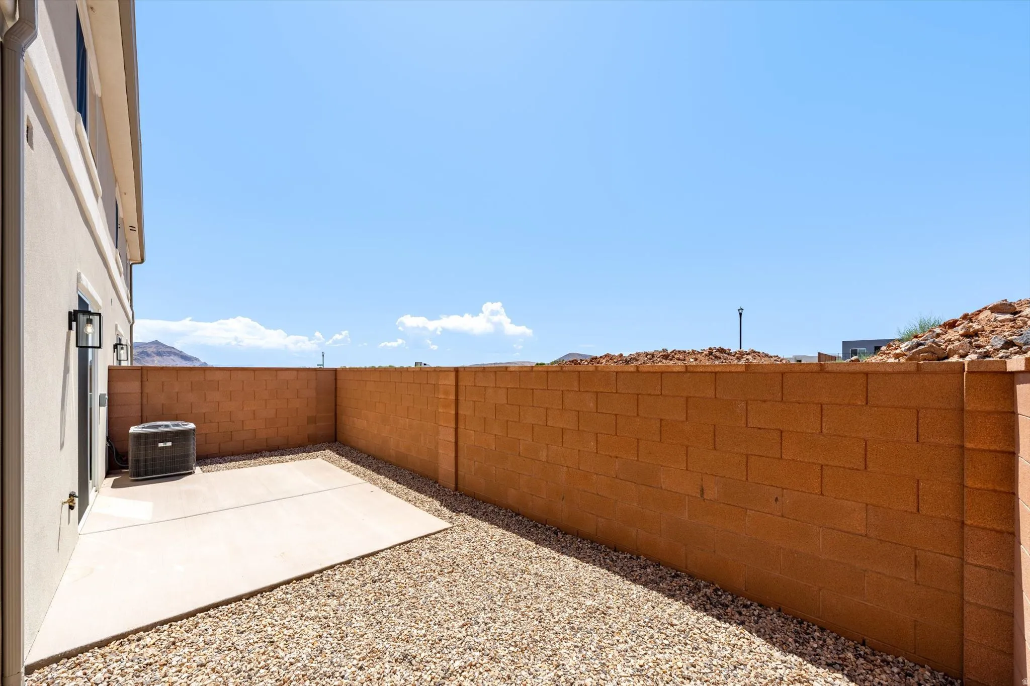 Private courtyard featuring a concrete patio, gravel landscaping, and a block wall perimeter
