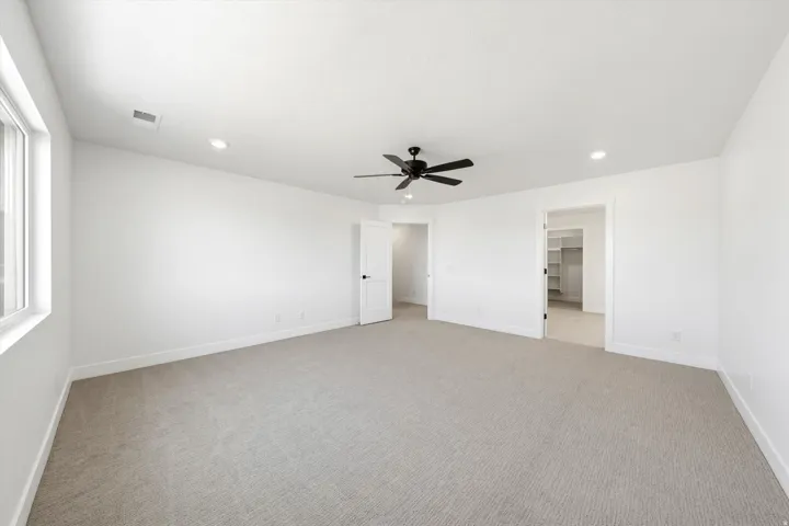 Spacious room featuring neutral carpet, white walls, recessed lighting, and a modern ceiling fan